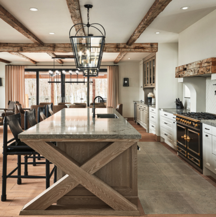 Rustic kitchen with wooden beams, large island, and a black and gold range.