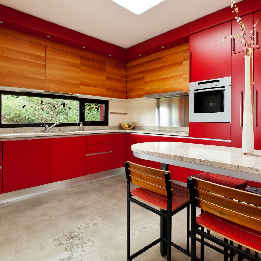 Modern kitchen with red cabinets, wood paneling, and island with bar stools.