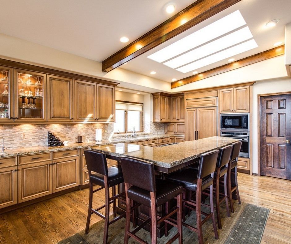 Kitchen with wooden cabinets, granite countertops, and a large island with bar stools.
