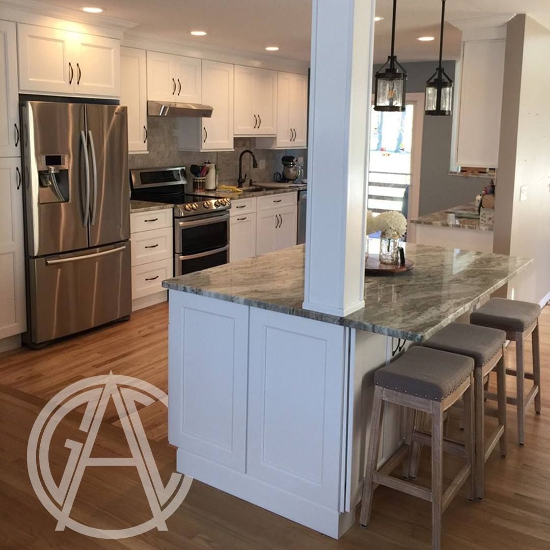 White kitchen with island, stainless steel appliances, and wood floors.
