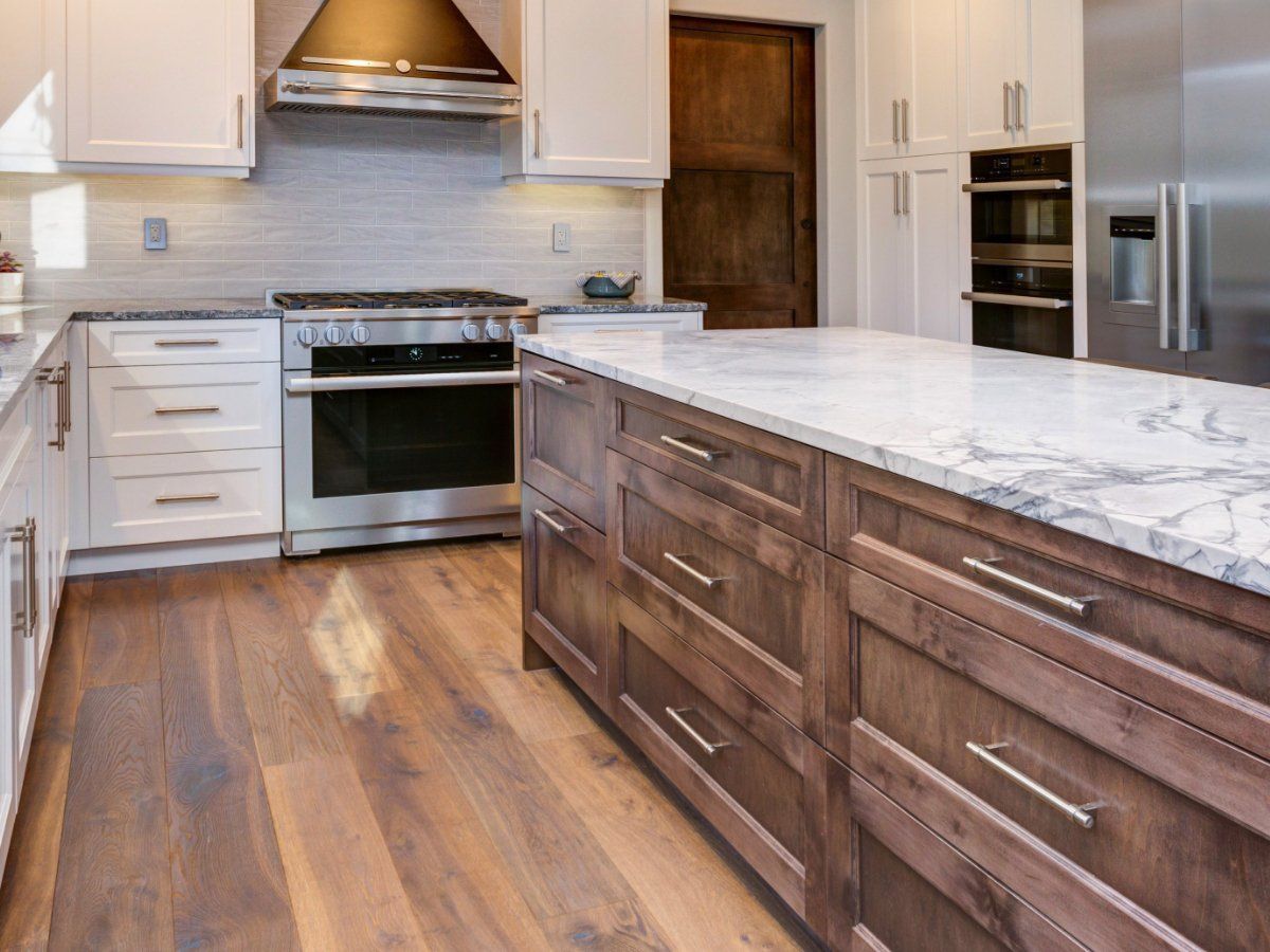 Kitchen with white cabinets, stainless steel appliances, and a wood island with a marble countertop.