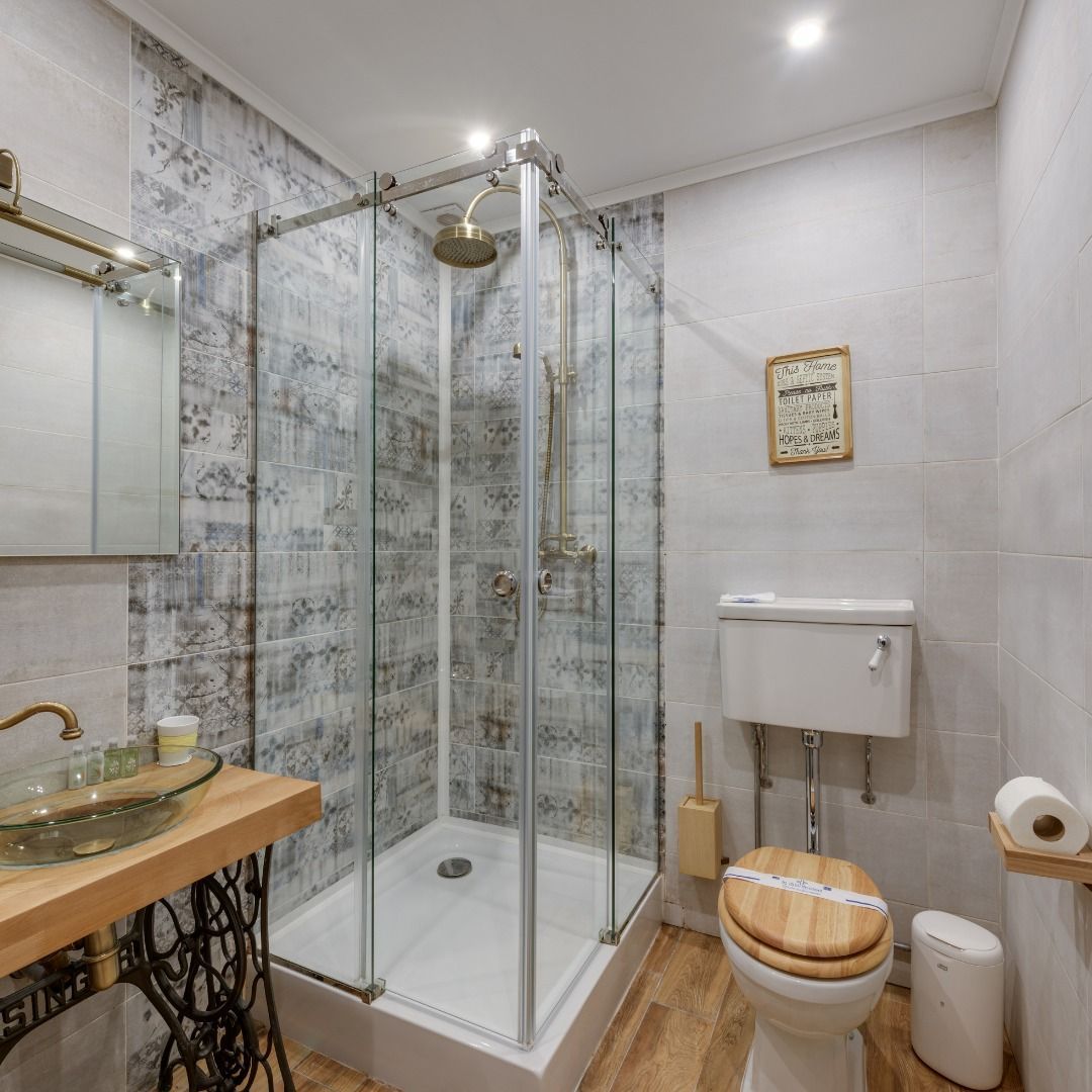 Bathroom with shower, toilet, sink on a wooden counter, and wood floor.