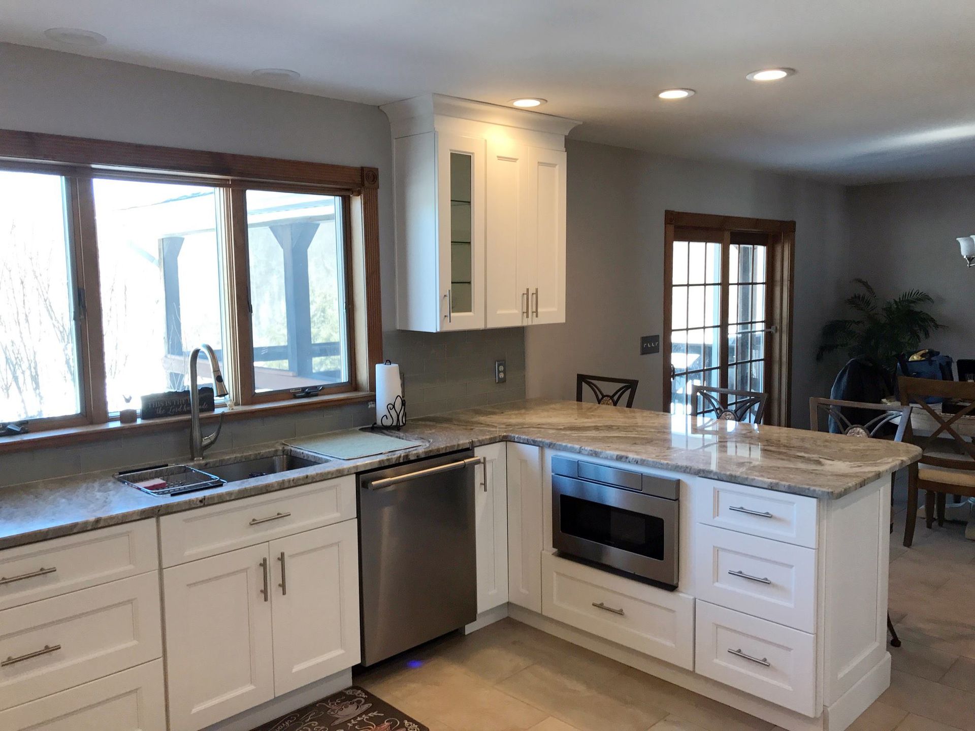 White kitchen with granite countertops, stainless steel appliances, and a window overlooking a deck.