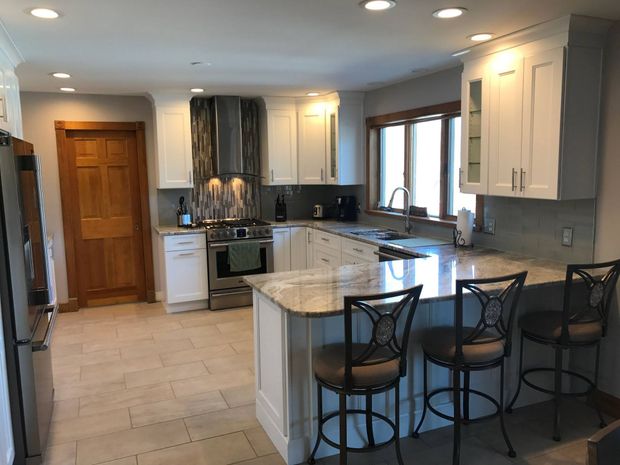 Kitchen with white cabinets, granite countertops, and bar stools.