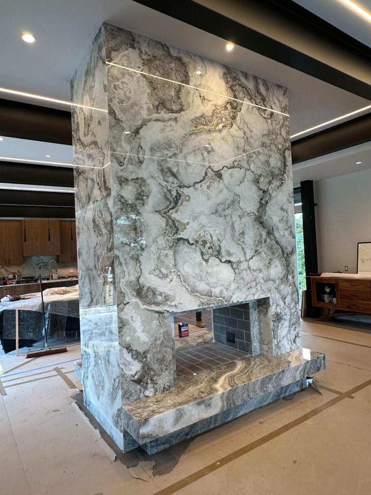 Marble fireplace in a modern interior, featuring gray and white veining, hearth, and rectangular opening.