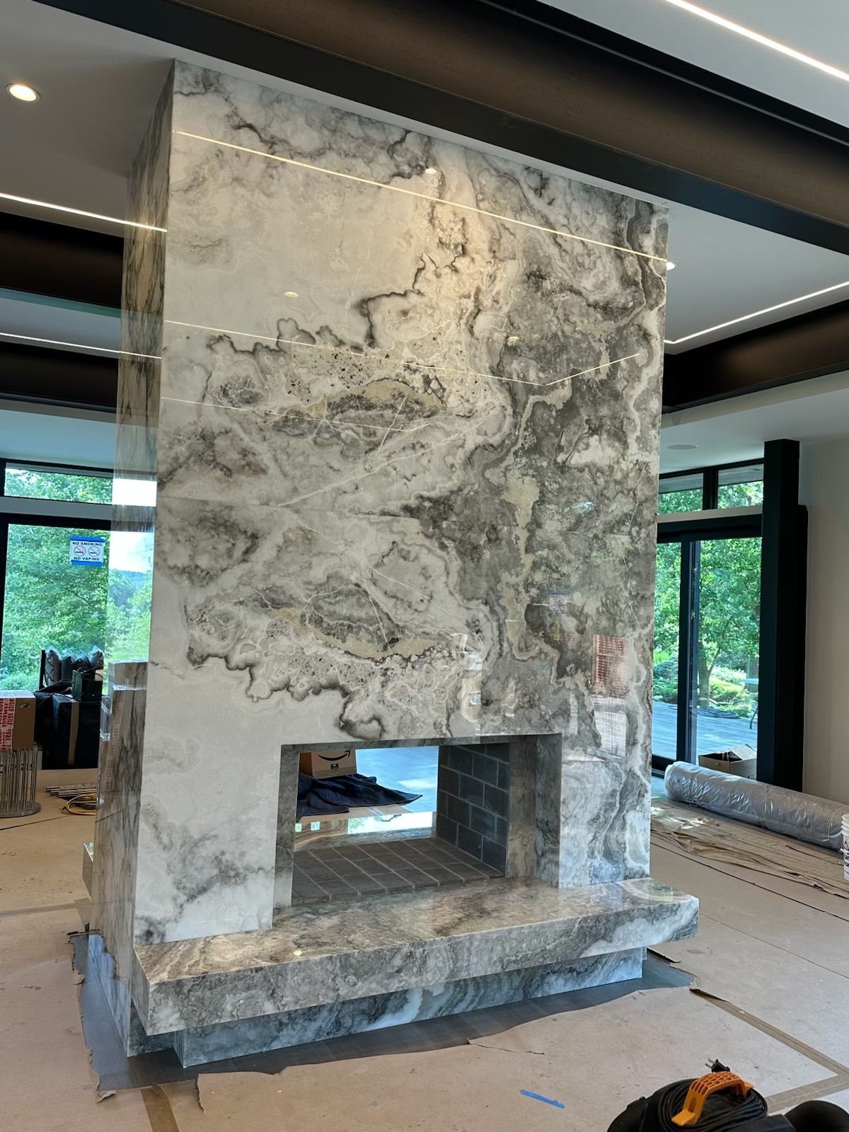 Marble fireplace with gray and white veining, set in a modern home. Firebox is visible.