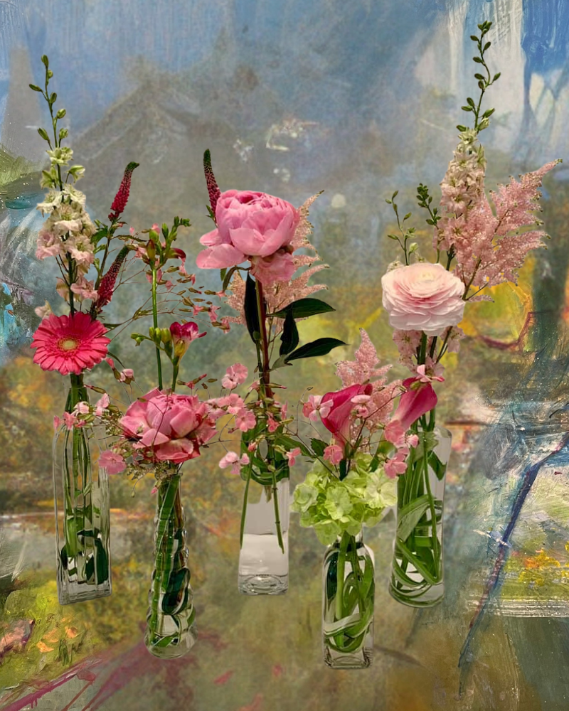 Vases of pink and white flowers arranged before a soft abstract painting backdrop