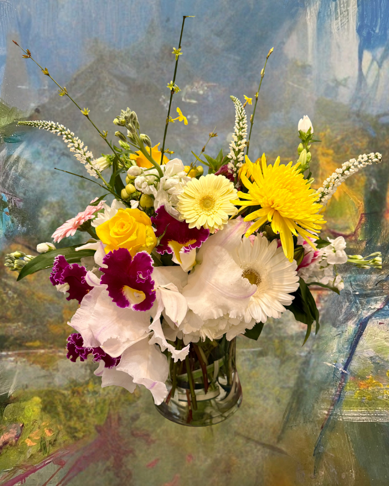 Colorful bouquet of daisies and wildflowers in a glass vase against a painterly blue and green background