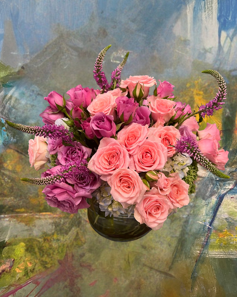 Pink rose and purple floral bouquet in a vase against a soft abstract painted background