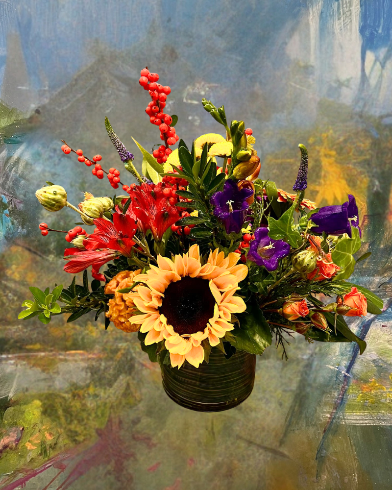 Colorful bouquet with sunflowers, red and purple flowers in a vase against a painted background