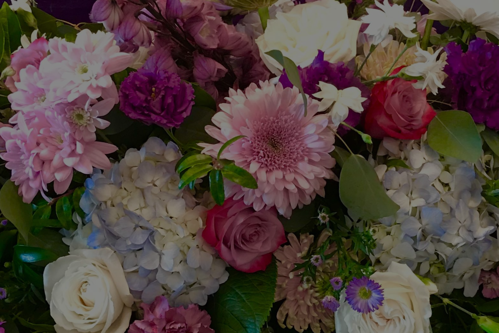 Assorted pink, purple, white, and cream flowers arranged in a dense bouquet.