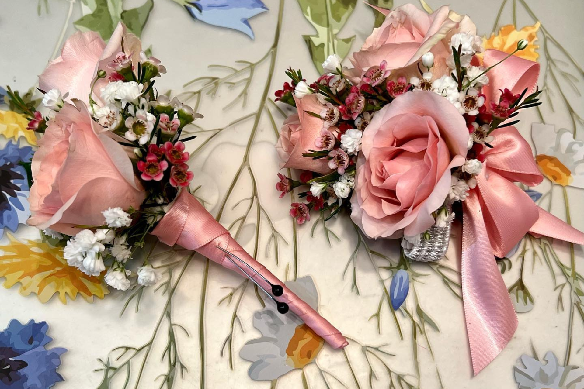 Two pink floral cone bouquets with roses and baby's breath on a patterned fabric background