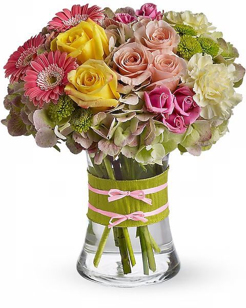Colorful mixed rose bouquet in a clear glass vase with a pink ribbon