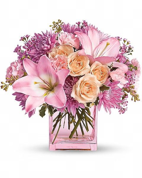 Pink and peach flowers in a square glass vase.