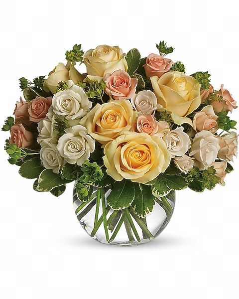 Bouquet of yellow, peach, and white roses in a clear glass bowl, surrounded by green foliage.
