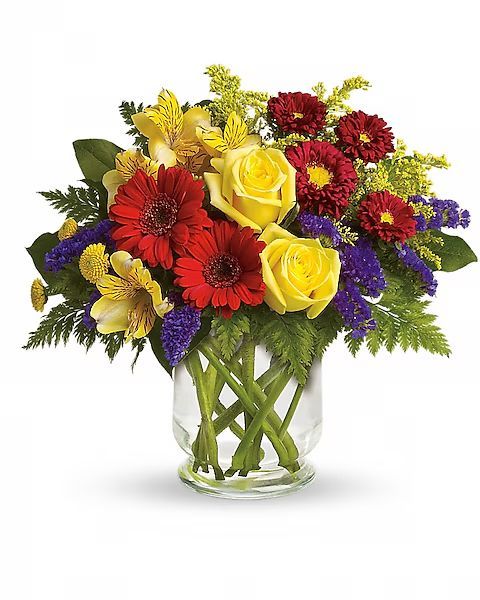 Colorful flower arrangement in a clear glass vase, featuring red, yellow, and purple blooms.