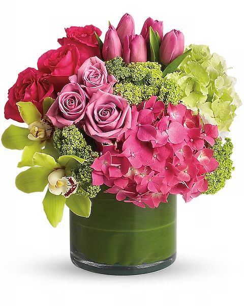 A floral arrangement with pink roses, tulips, and hydrangea in a green glass vase.