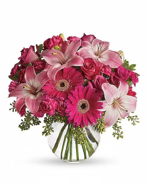 Pink flower arrangement in a clear, round vase. Includes lilies, gerberas, and roses.