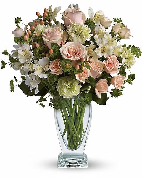 Bouquet of pink roses, white lilies, and greenery in a clear vase.
