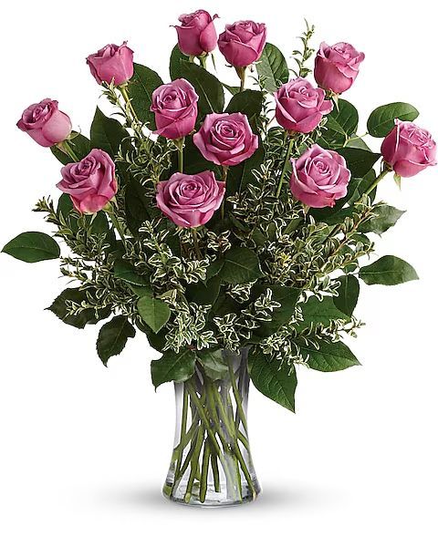 Bouquet of pink roses in a clear glass vase, surrounded by greenery.