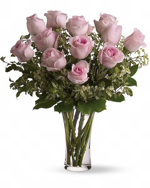 Pink roses in a clear glass vase, surrounded by greenery.