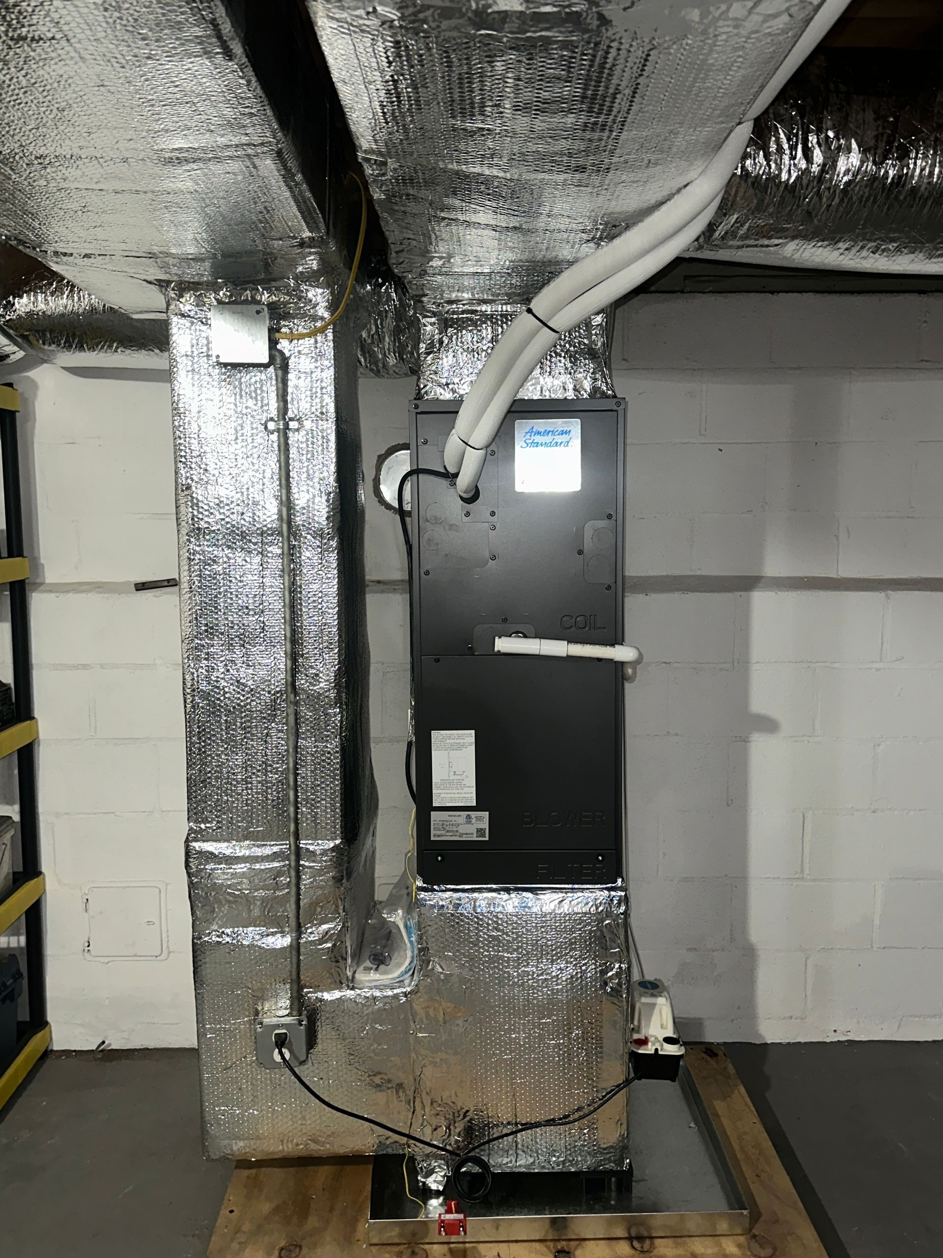 A black air conditioner is sitting in a basement.