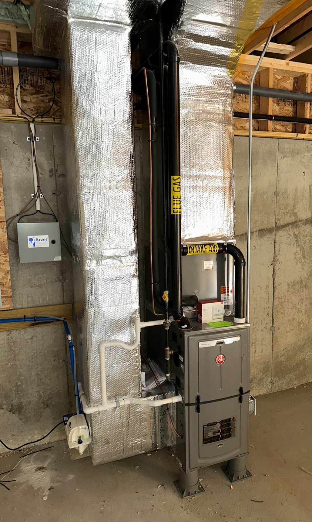 A furnace is sitting in a basement next to a wall.