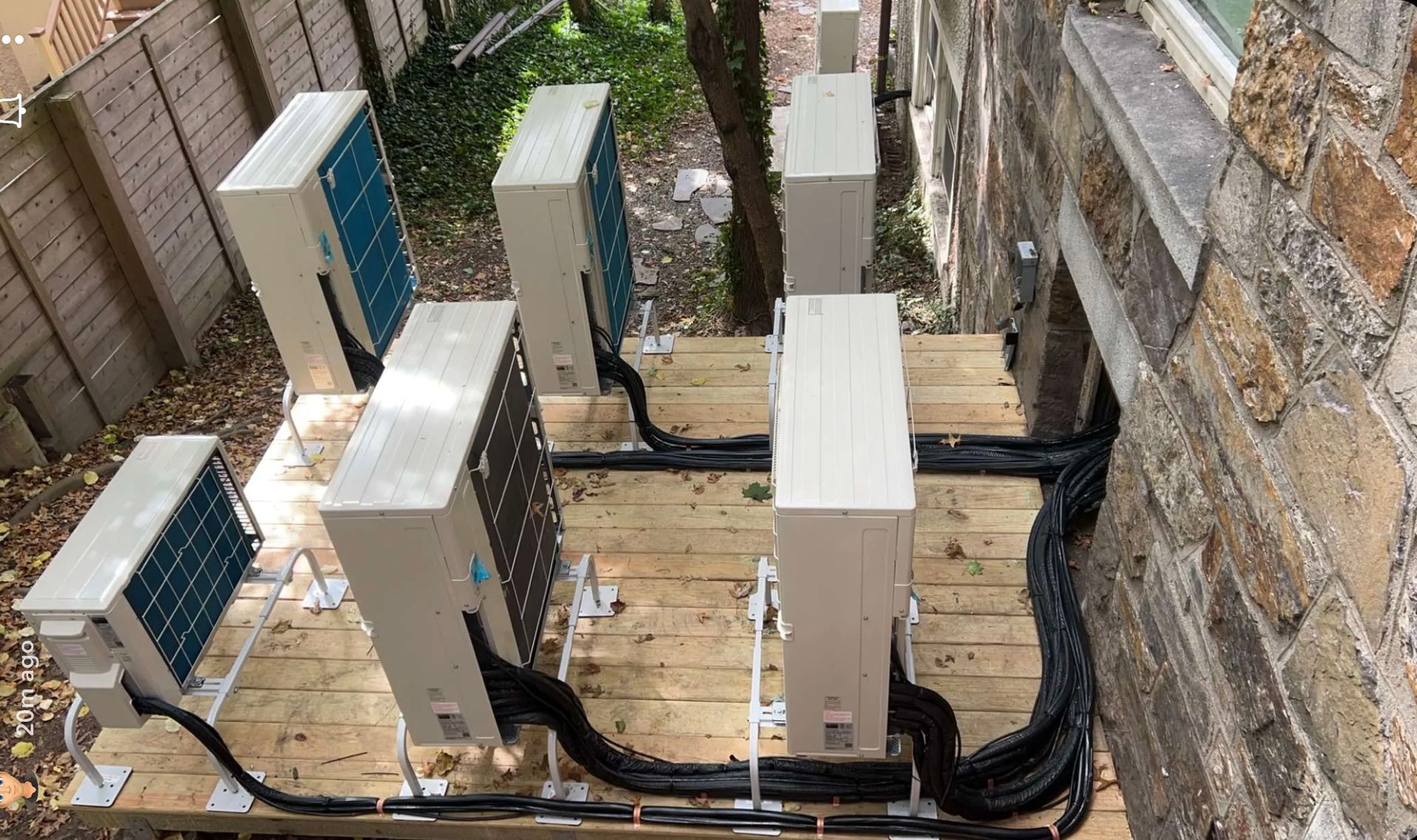 A row of air conditioners are sitting on top of a wooden deck.