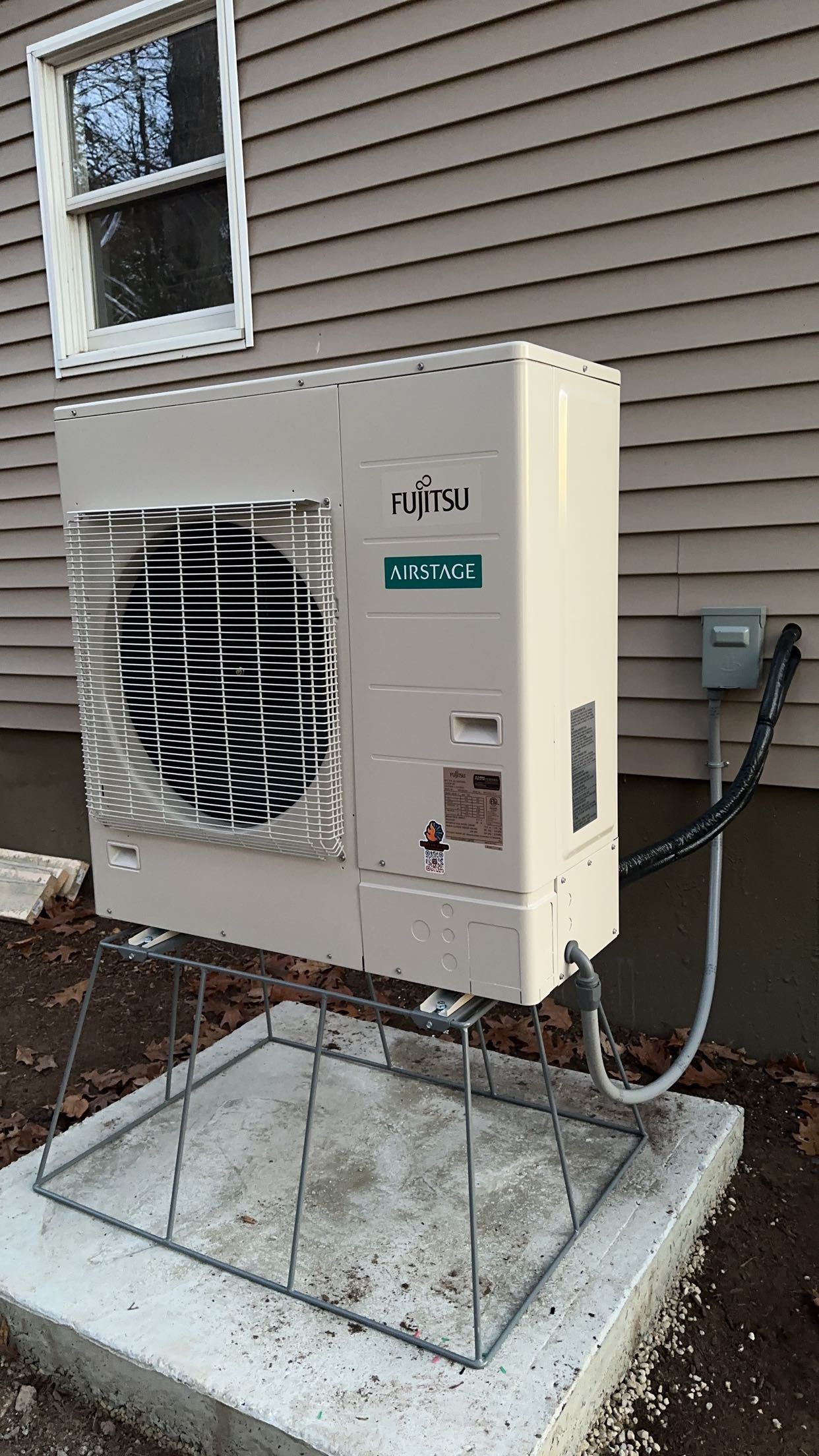 a white air conditioner is sitting on top of a concrete block next to a house