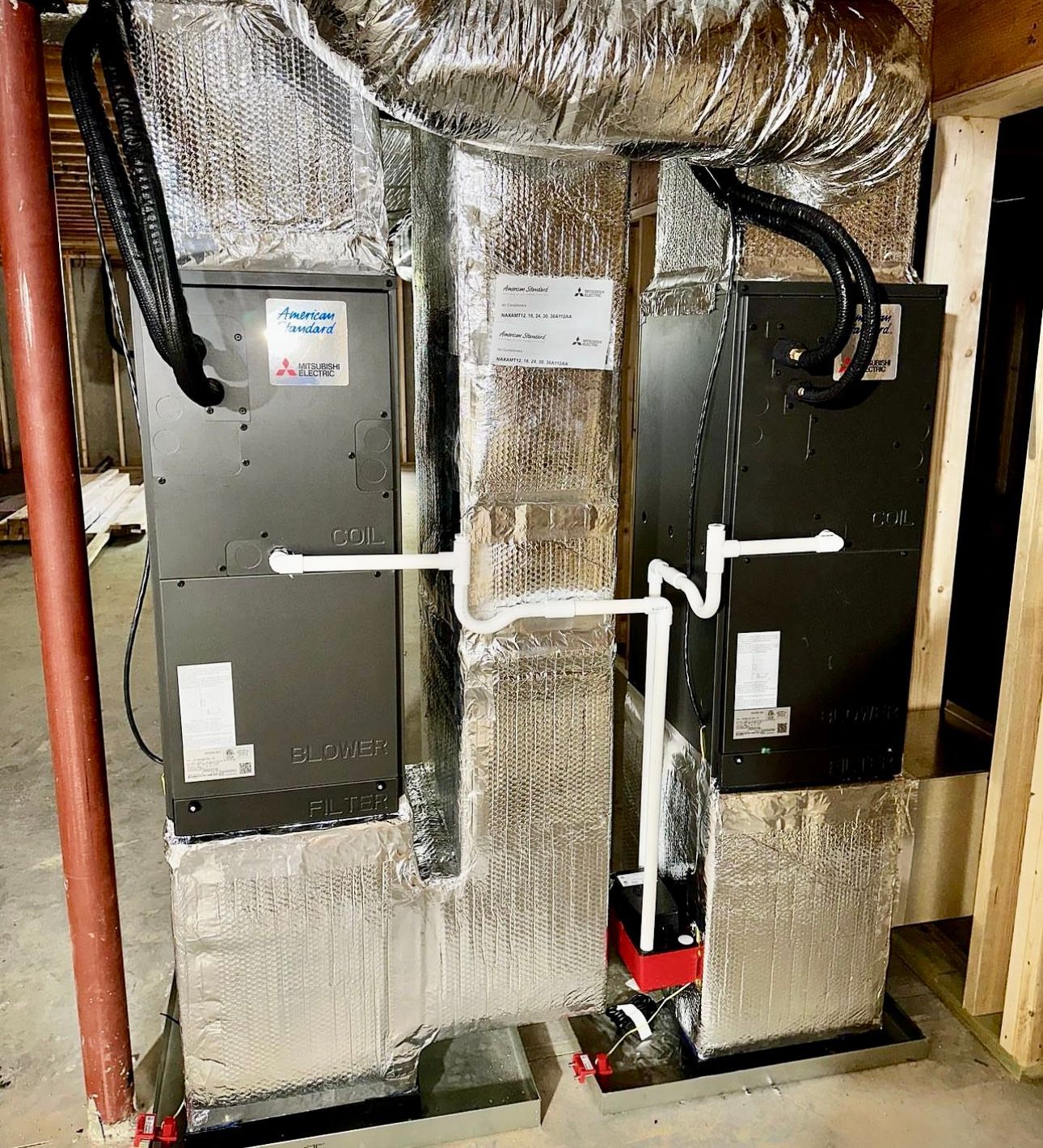 two air conditioners are sitting next to each other in a basement