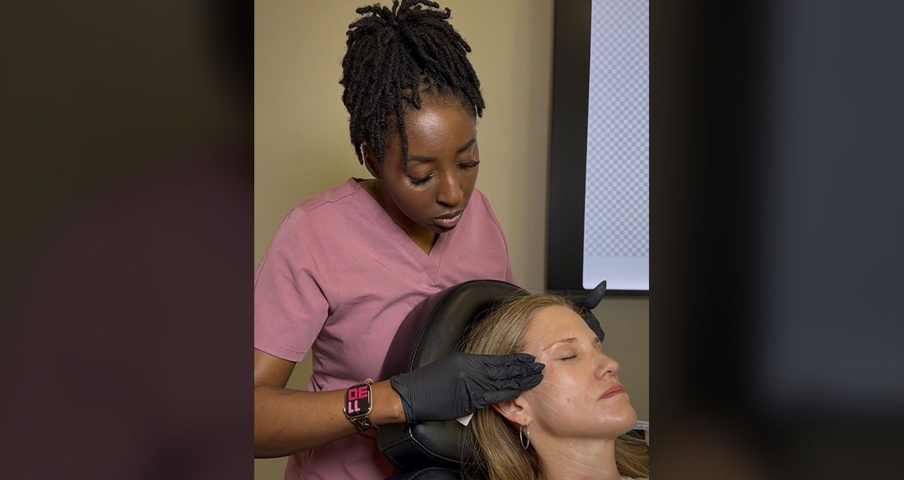 Aesthetic treatment being applied to a woman’s face by a clinician wearing gloves in a spa setting