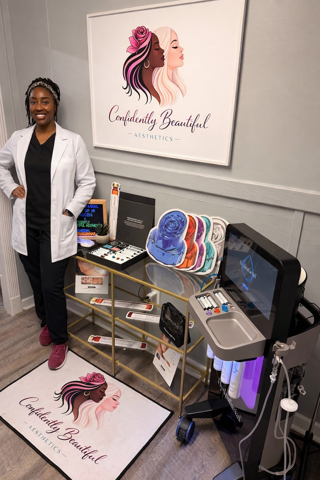 Woman in white coat standing beside a salon display with logo sign, color swatches, and a manicure table
