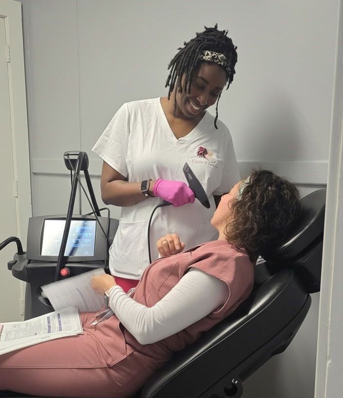 Dentist wearing gloves examines a patient reclining in a dental chair with pink bib and gloves.
