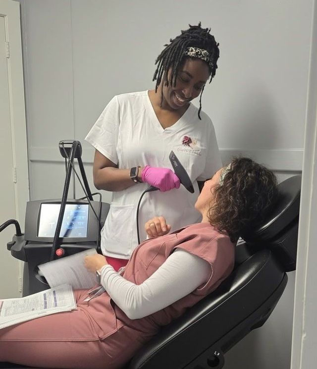 Dentist wearing gloves examines a patient reclining in a dental chair with pink bib and gloves.