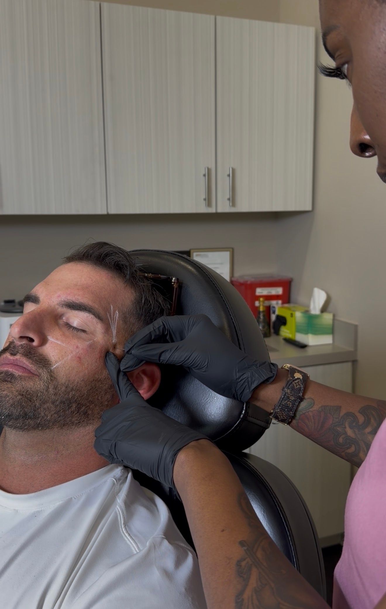 A person wearing gloves trims another person’s hair in a salon chair.