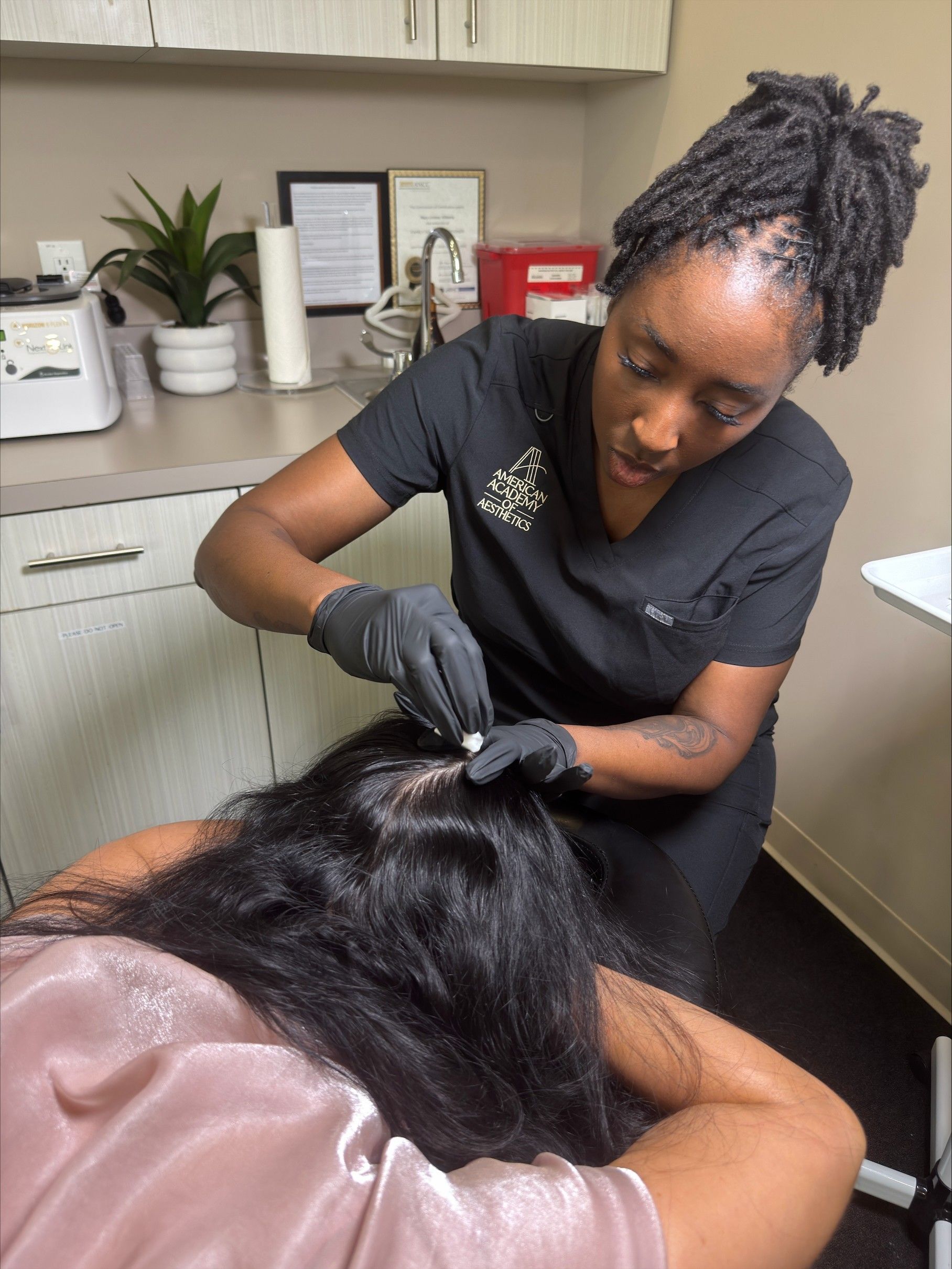 Hair stylist braiding a client’s hair in a salon chair, with products and tools on a nearby counter.