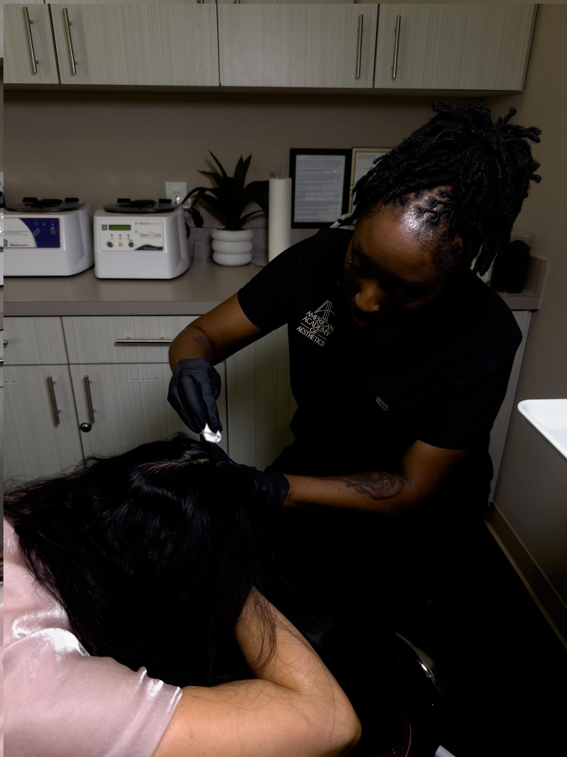 Person braiding another person's hair in a salon with gloves on