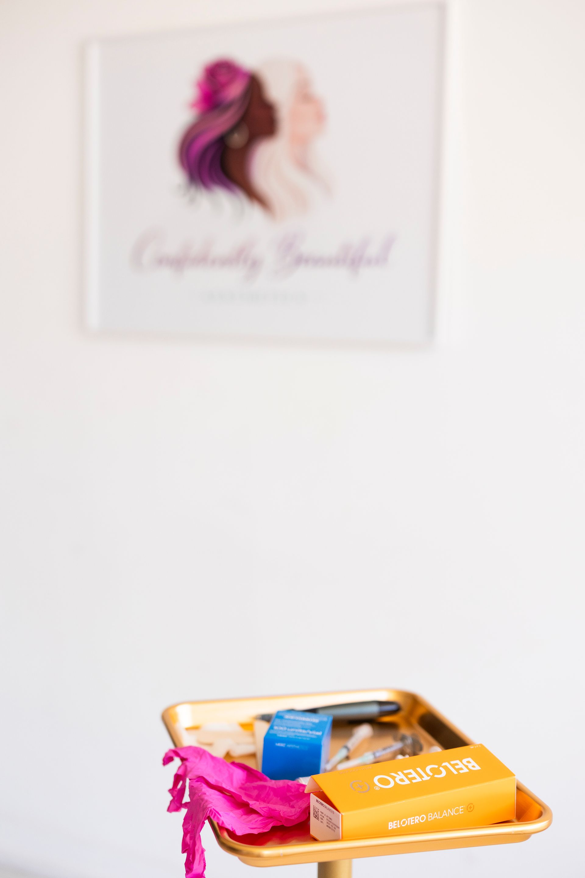 Orange tray with makeup and nail supplies on a white shelf beneath a blurred wall print
