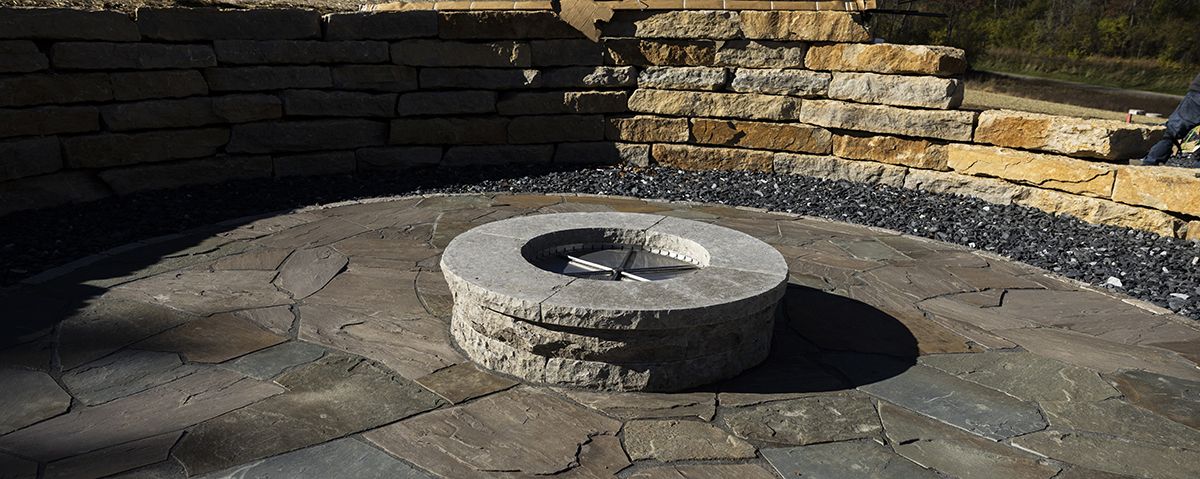 A fire pit is sitting in the middle of a stone patio.