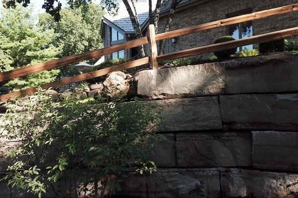 A stone wall with a wooden fence in front of a house
