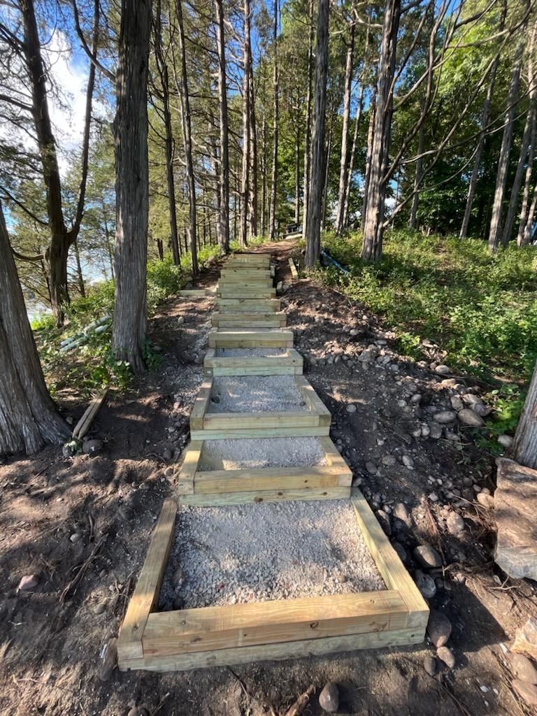 A wooden staircase in the middle of a forest leading to a lake.