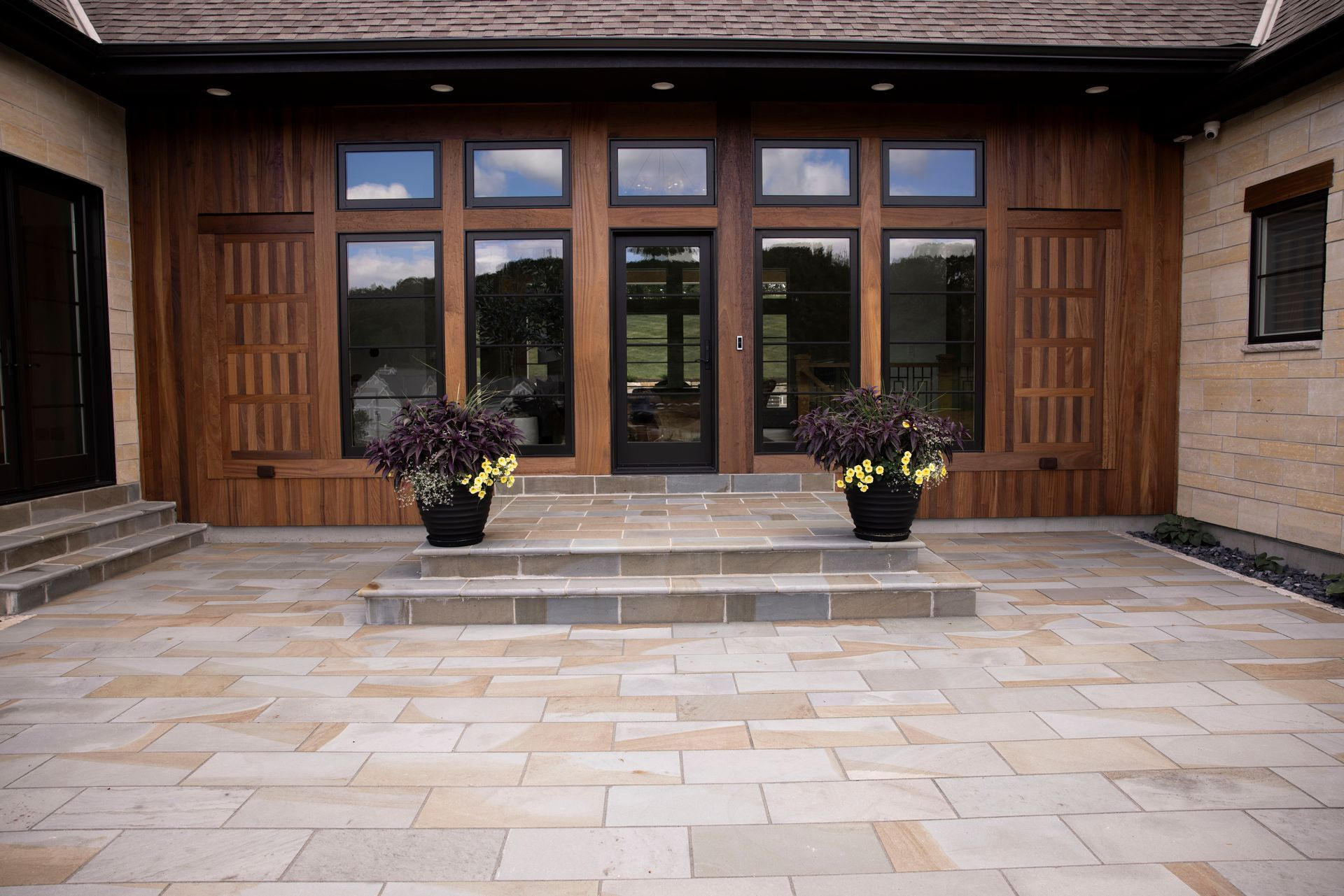 There are two potted plants in front of the door of a house.