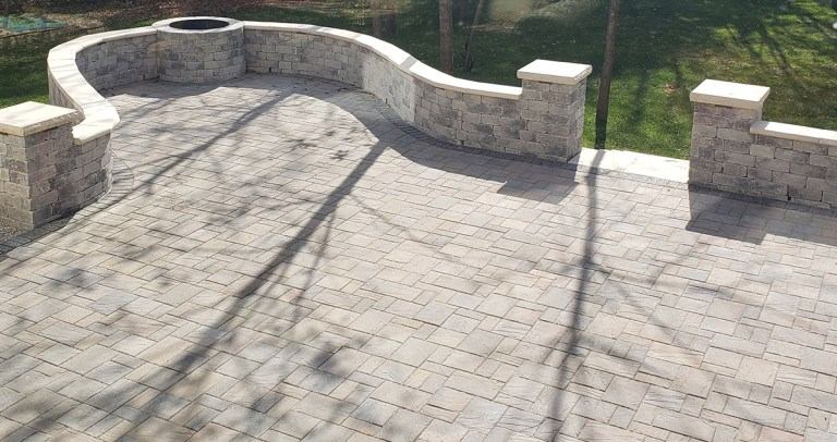 A brick patio with a fire pit in the middle of it.