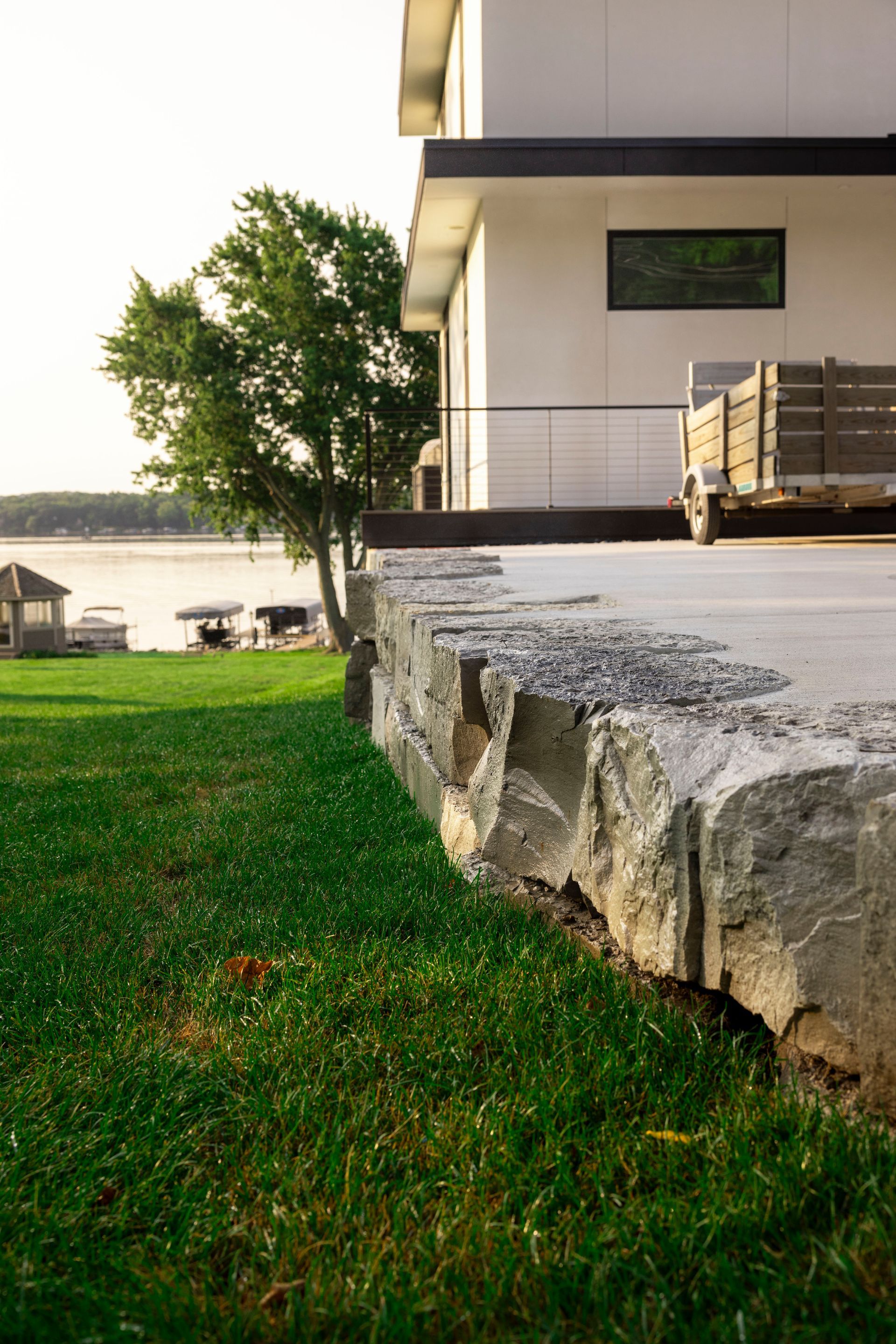 A house with a large lawn in front of it and a lake in the background.