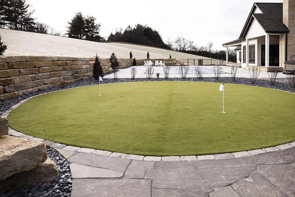 A house with a putting green in front of it.
