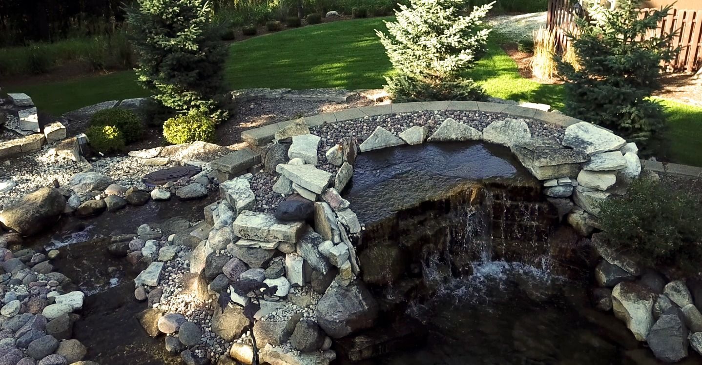 A small waterfall is surrounded by rocks in a garden.