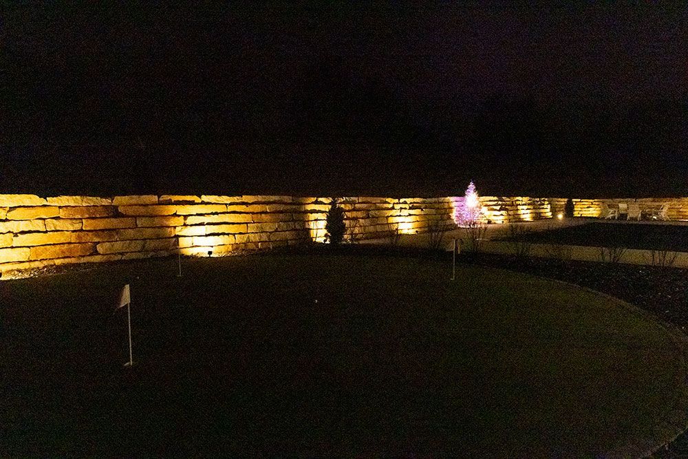 A golf course is lit up at night with a fountain in the background.