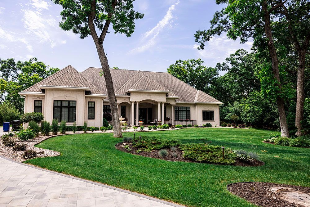 A large house with a lush green lawn and trees in front of it.