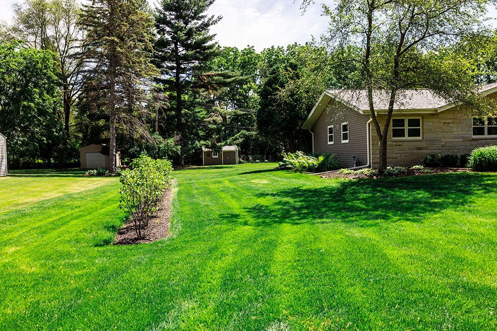 A house with a large lush green lawn in front of it.