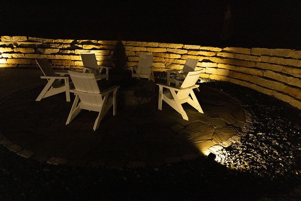A group of chairs are sitting around a fire pit at night.